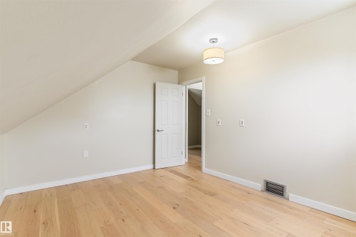 Hardwood flooring, sloped ceiling, drum light fixture, white interior doors - 12337 128 Avenue Nw, Edmonton, AB - Indoor Photo Showing Other Room
