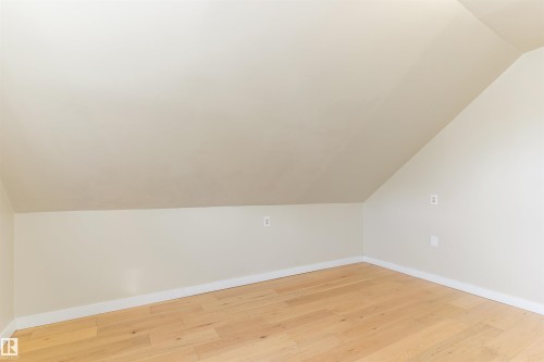 Light-toned wood-finish flooring, sloped ceiling, and neutral wall tones - 12337 128 Avenue Nw, Edmonton, AB - Indoor Photo Showing Other Room
