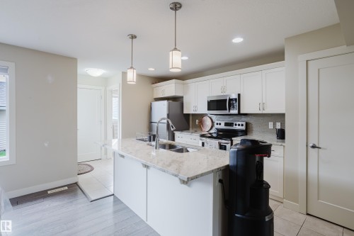 Kitchen featuring a central island with dual pendant lighting, stainless steel appliances, white cabinetry, and light-toned countertops - 124 Cy Becker Boulevard Nw, Edmonton, AB - Indoor Photo Showing Kitchen With Stainless Steel Kitchen With Double Sink With Upgraded Kitchen