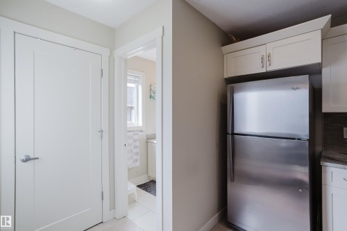 Stainless steel refrigerator with upper cabinetry, complemented by a white panel interior door with brushed nickel hardware - 124 Cy Becker Boulevard Nw, Edmonton, AB - Indoor