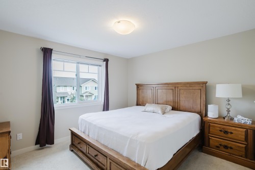Neutral-toned bedroom featuring a large window with white trim, light-colored carpeting, a ceiling-mounted flush light fixture, and light beige wall paint - 124 Cy Becker Boulevard Nw, Edmonton, AB - Indoor Photo Showing Bedroom
