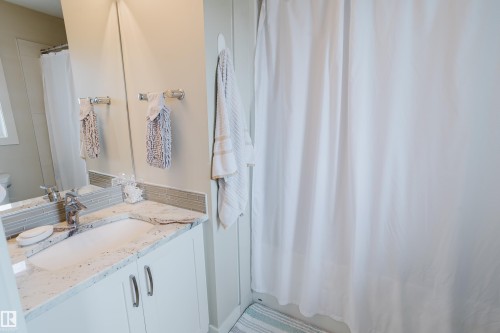 Bathroom vanity featuring an integrated sink, granite-style countertop, and white cabinetry with brushed nickel hardware - 124 Cy Becker Boulevard Nw, Edmonton, AB - Indoor Photo Showing Bathroom