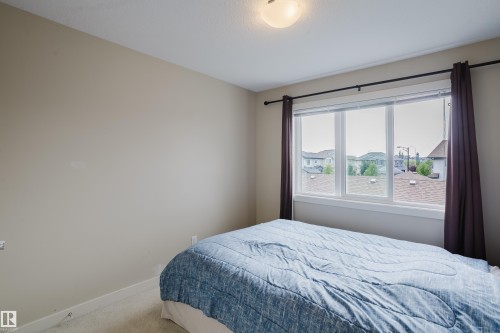 Room featuring a large triple-pane window, neutral wall paint, and plush carpet flooring - 124 Cy Becker Boulevard Nw, Edmonton, AB - Indoor Photo Showing Bedroom
