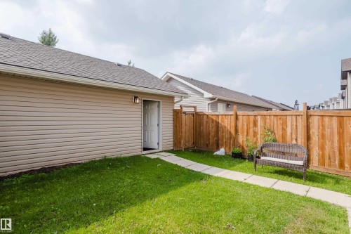 Private rear yard featuring a wooden privacy fence, a concrete paver pathway, and a side access door - 124 Cy Becker Boulevard Nw, Edmonton, AB - Outdoor