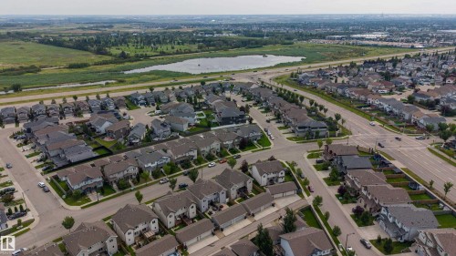 Aerial view showcasing this residential community featuring new construction homes with dark architectural roofing, manicured landscaping, and tree-lined streets - 124 Cy Becker Boulevard Nw, Edmonton, AB - Outdoor With View
