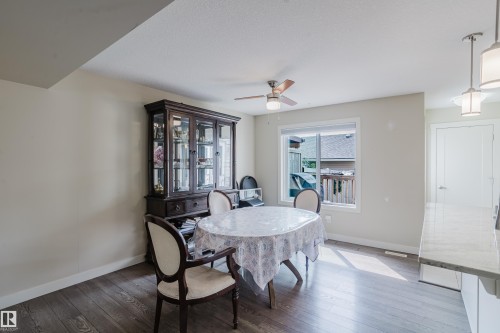 Dining area featuring wood-finish flooring, a window offering exterior light, a ceiling fan with integrated lighting, and a white interior door - 124 Cy Becker Boulevard Nw, Edmonton, AB - Indoor Photo Showing Dining Room