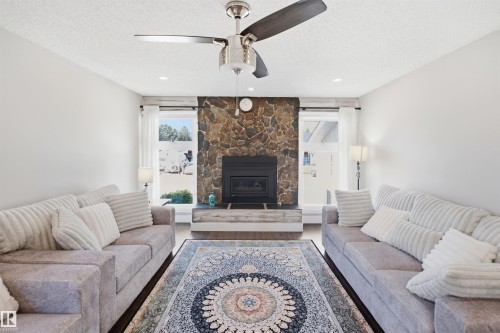 Stone-faced fireplace with a dark metal insert, flanked by two windows - 3515 20 Ave Nw, Edmonton, AB - Indoor Photo Showing Living Room With Fireplace