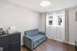 Wood-finish flooring, white walls, and a contemporary flush-mount ceiling light - 