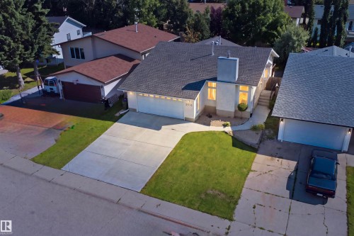 Exterior featuring a light-colored facade, dark shingle roof, attached garage, and a concrete driveway - 3515 20 Ave Nw, Edmonton, AB - Outdoor