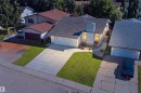 Exterior featuring a light-colored facade, dark shingle roof, attached garage, and a concrete driveway - 3515 20 Ave Nw, Edmonton, AB 