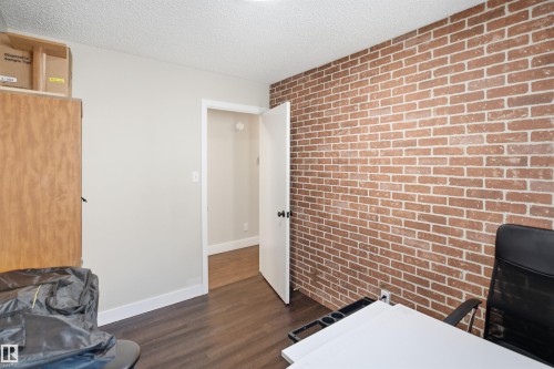 Brick accent wall with wood-finish flooring - 3515 20 Ave Nw, Edmonton, AB - Indoor Photo Showing Other Room
