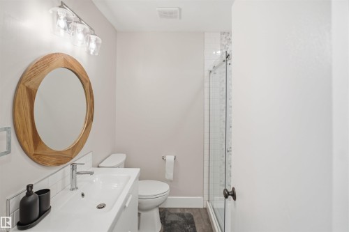 Wood-finish flooring, white vanity with integrated sink, chrome faucet, and a glass-enclosed shower with tile surround - 3515 20 Ave Nw, Edmonton, AB - Indoor Photo Showing Bathroom