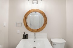 Bathroom featuring a circular wood-framed mirror, undermount sink, and polished chrome faucet - 
