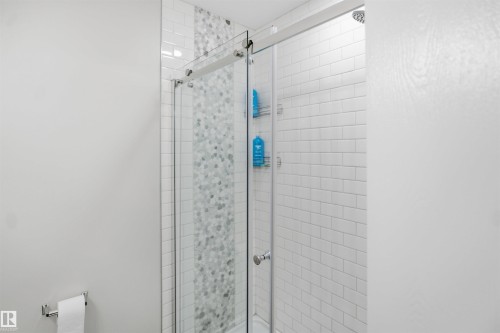 Glass-enclosed shower with a sliding door, white subway tile surround, and a mosaic tile accent strip - 3515 20 Ave Nw, Edmonton, AB - Indoor Photo Showing Bathroom