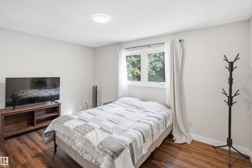 Room featuring wood-finish flooring, a white ceiling with a flush-mount light fixture, and a window with white trim - 3515 20 Ave Nw, Edmonton, AB - Indoor Photo Showing Bedroom