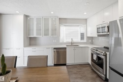 Modern kitchen featuring white cabinetry, stainless steel appliances, a bay window, and recessed lighting - 
