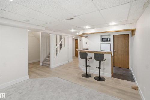 Built-in wet bar with wood-finish countertop, recessed lighting, wood-finish flooring, carpeted stairs with painted white balusters, and a drop ceiling - 3515 20 Ave Nw, Edmonton, AB - Indoor