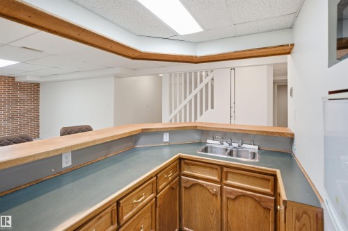 Built-in bar with wood-finish cabinetry, stainless steel sink, and ample countertop space - 3515 20 Ave Nw, Edmonton, AB - Indoor