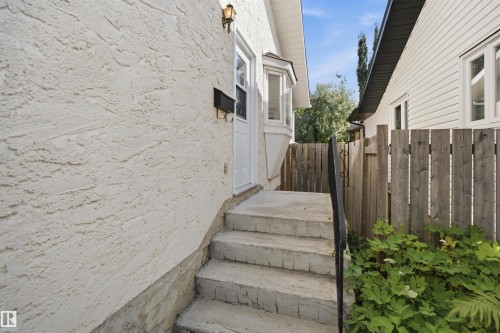 Stucco exterior with a bay window, concrete steps, and a black metal handrail - 3515 20 Ave Nw, Edmonton, AB - Outdoor