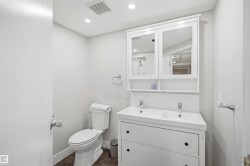 Dual-sink vanity with white cabinetry, tile backsplash, and mirrored medicine cabinet - 