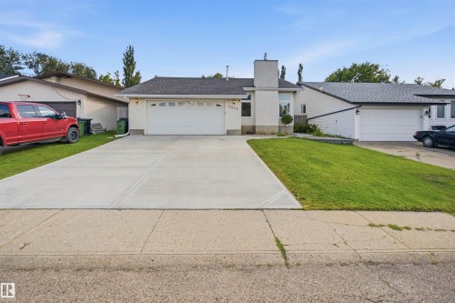 White stucco exterior with a multi-level roofline, featuring an attached garage with a white door, and a concrete driveway - 3515 20 Ave Nw, Edmonton, AB - Outdoor
