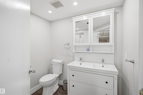Dual-sink vanity with white cabinetry, tile backsplash, and mirrored medicine cabinet - 3515 20 Ave Nw, Edmonton, AB - Indoor Photo Showing Bathroom