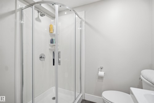 Curved glass shower enclosure with chrome hardware and a built-in corner shelf - 3515 20 Ave Nw, Edmonton, AB - Indoor Photo Showing Bathroom