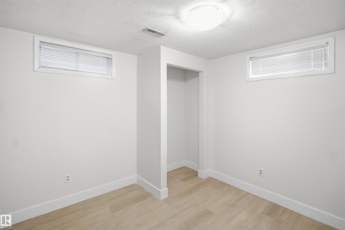 Recessed open closet, light wood-finish flooring, two rectangular windows, flush-mount ceiling light, and white painted walls - 3515 20 Ave Nw, Edmonton, AB - Indoor Photo Showing Other Room
