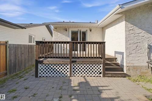 Wooden deck with lattice skirting, stone paver patio, and sliding glass door - 3515 20 Ave Nw, Edmonton, AB - Outdoor With Deck Patio Veranda With Exterior