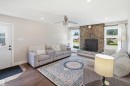 Stone-faced fireplace with a built-in firebox, wood-finish flooring, recessed lighting, ceiling fan, and multiple windows with white trim - 3515 20 Ave Nw, Edmonton, AB 