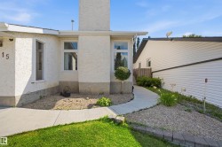 Stucco exterior with a prominent chimney feature, white window frames, concrete pathway, and gravel landscaping - 