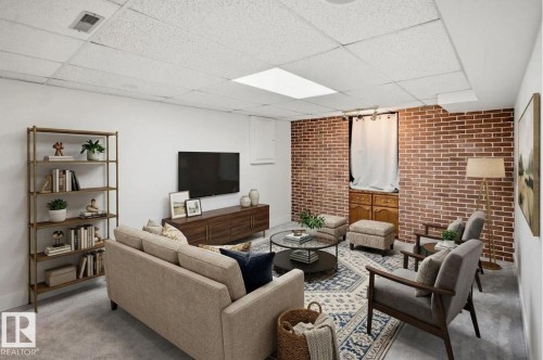 Exposed brick accent wall, white painted walls, dropped ceiling, integrated lighting, and carpeted flooring - 3515 20 Ave Nw, Edmonton, AB - Indoor