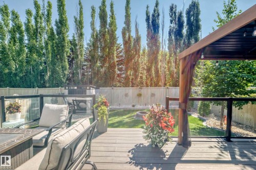 Expansive composite decking featuring glass panel railings and a built-in pergola - 823 77 Street Sw, Edmonton, AB - Outdoor
