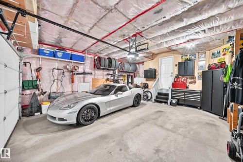 Spacious garage featuring a concrete floor, overhead garage door, built-in storage shelving, and a pedestrian door with steps - 823 77 Street Sw, Edmonton, AB - Indoor Photo Showing Garage
