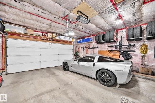Two-car garage featuring a concrete floor, insulated ceiling, a white panel garage door, and dedicated wall-mounted shelving - 823 77 Street Sw, Edmonton, AB - Indoor Photo Showing Garage