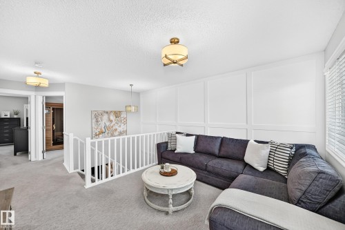 Upper-level living area with carpet flooring and board and batten wall detailing - 823 77 Street Sw, Edmonton, AB - Indoor Photo Showing Living Room