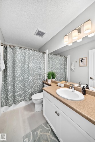 Bathroom featuring a white vanity with double-door cabinetry, a single basin sink, and a speckled countertop - 823 77 Street Sw, Edmonton, AB - Indoor Photo Showing Bathroom