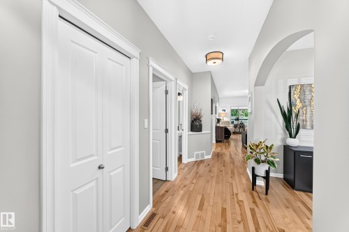 Hallway featuring wood-finish flooring, an arched doorway, white trim, and a semi-flush mount ceiling light - 823 77 Street Sw, Edmonton, AB - Indoor Photo Showing Other Room