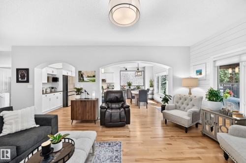 Open-concept living area featuring light wood-finish flooring, white walls, and a contemporary ceiling fixture - 823 77 Street Sw, Edmonton, AB - Indoor Photo Showing Living Room
