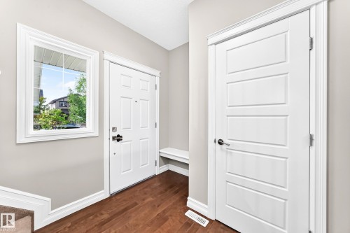 Wood-finish flooring with crisp white trim, a multi-panel interior door, and a built-in bench - 4212 Charles Close Sw, Edmonton, AB - Indoor Photo Showing Other Room