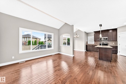 Hardwood-finish flooring, vaulted ceiling, large picture window, kitchen island with sink, and dark wood cabinetry - 4212 Charles Close Sw, Edmonton, AB - Indoor