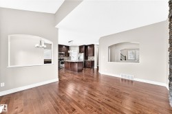 Hardwood flooring, arched wall cut-outs, high ceilings, dark wood-finish cabinetry, and a stacked stone-finish accent wall - 