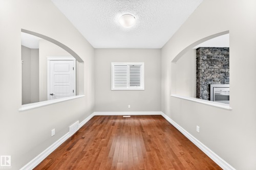 Warm wood-finish flooring, light neutral wall paint, and white trim - 4212 Charles Close Sw, Edmonton, AB - Indoor Photo Showing Other Room