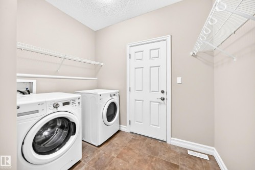 Utility room with tile flooring, neutral wall tones, and overhead wire shelving - 4212 Charles Close Sw, Edmonton, AB - Indoor Photo Showing Laundry Room