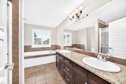 Double vanity with granite-style countertop, dual undermount sinks, and chrome fixtures - 4212 Charles Close Sw, Edmonton, AB - Indoor Photo Showing Bathroom