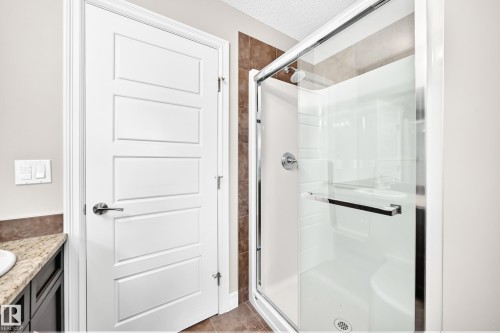Walk-in shower with clear glass enclosure, chrome fixtures, and tiled surround - 4212 Charles Close Sw, Edmonton, AB - Indoor Photo Showing Bathroom