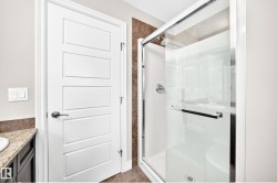 Walk-in shower with clear glass enclosure, chrome fixtures, and tiled surround - 