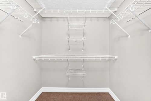 Dedicated storage space featuring multiple white wire shelving units and a textured carpeted floor - 4212 Charles Close Sw, Edmonton, AB - Indoor With Storage