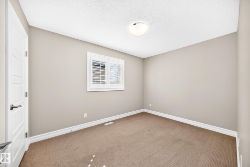 Neutral-toned walls, textured ceiling, and a white interior door with dark hardware - 4212 Charles Close Sw, Edmonton, AB - Indoor Photo Showing Other Room