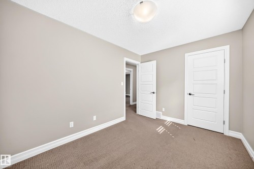 Neutral-toned walls, textured ceiling, flush mount ceiling light, and panel doors with dark hardware - 4212 Charles Close Sw, Edmonton, AB - Indoor Photo Showing Other Room